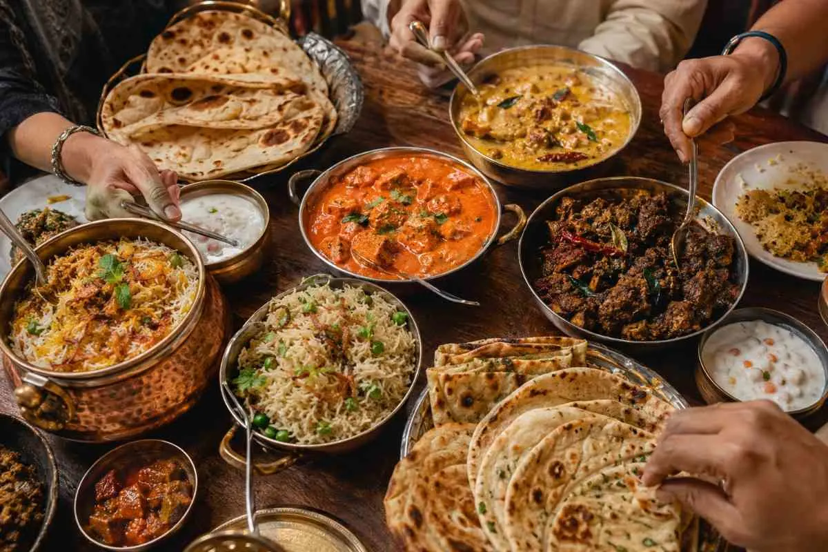Close-up of Indian banquet dishes including coconut curry, butter chicken, and naan bread served together